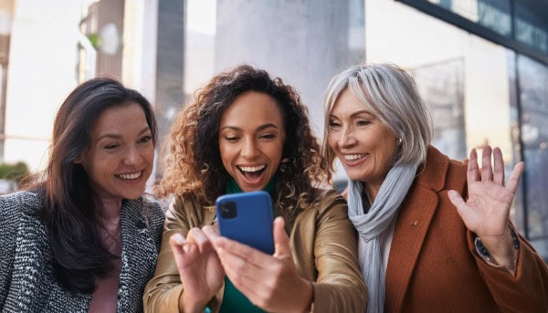 trois femmes regardent un vidéo sur une smartphone